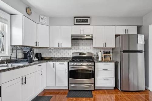 uma cozinha com armários brancos e um frigorífico de aço inoxidável em Rockaway 3 bedroom suite by the Sea. em Wave Crest