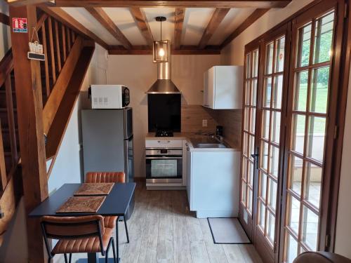 a kitchen with white appliances and a table and chairs at Le manège Gite Le phare in Sainte-Marie-au-Bosc