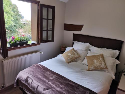 1 cama con sábanas y almohadas blancas en una habitación con ventana en Le manège Gite Le phare en Sainte-Marie-au-Bosc