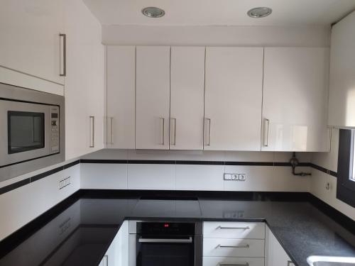 a white kitchen with white cabinets and a microwave at CAL JAN - CADÍ in Bellver de Cerdanya 