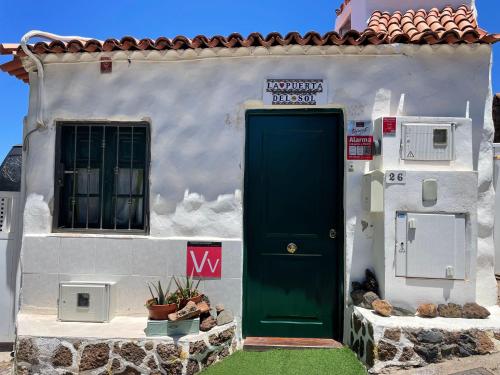 a white house with a green door and a window at La Puerta del Sol in Adeje