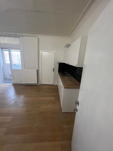 een lege keuken met witte kasten en een houten vloer bij Bkenkember Apart in Antwerpen