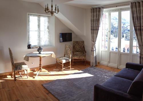 uma sala de estar com um sofá azul e uma mesa e cadeiras em Villa l'Orante em Lourdes