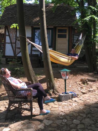 dos personas sentadas en una hamaca en un patio en Etno selo Krugerdorf, 