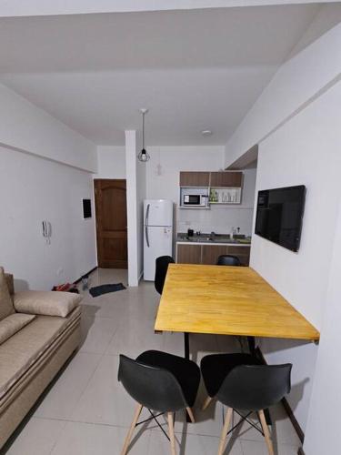 cocina y sala de estar con mesa de madera y sillas en Alvarado 1700 en Salta