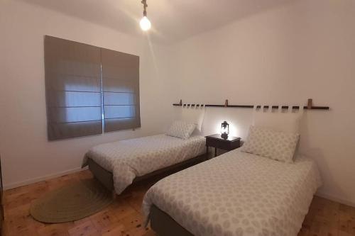 a bedroom with two beds and a window at Adcasinha em Arganil in Adcasal