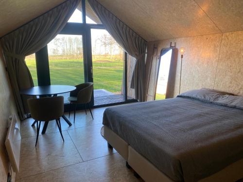 Schlafzimmer mit einem Bett, einem Tisch und einem Fenster in der Unterkunft Natuurhuisjes Lust en Last in Sommelsdijk