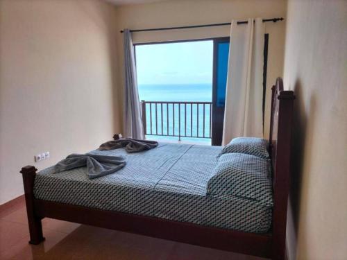 a bedroom with a bed with a view of the ocean at Casa Joãozinho De Lora in São Filipe