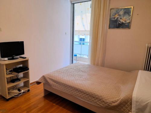 a bedroom with a bed and a television and a window at Condo in Kalamata - Park View in Kalamata