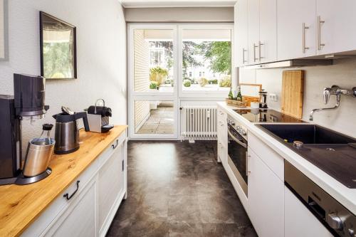 eine Küche mit weißen Schränken und einem großen Fenster in der Unterkunft Stilvolle Stadtoase, 116 qm, Parkblick, Wassernah, Parkplatz in Wilhelmshaven