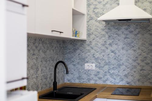 una cucina con carta da parati blu e bianca e un lavandino di Studio Apartments Summer Time a Kamenari