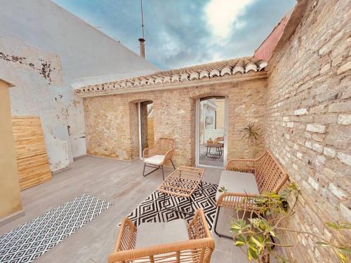 un patio avec des chaises et des tables ainsi qu'un mur en briques dans l'établissement Casa Albufera suite, à Valence