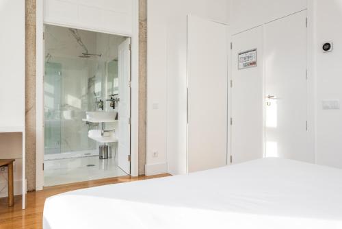 sypialnia z białymi szafkami i szklanym prysznicem w obiekcie Avenida Viana Boutique Suites w mieście Viana do Castelo