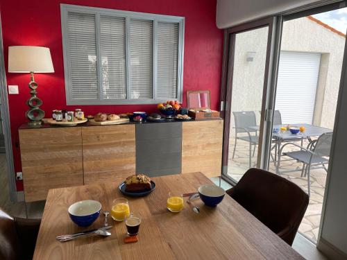 une salle à manger avec une table en bois et des murs rouges dans l'établissement Les Pertuis Rochelais, à Périgny