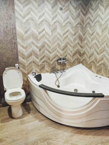 a bathroom with a white bath tub next to a toilet at Студия с Джакузи на Молодогвардейской in Mykolaiv