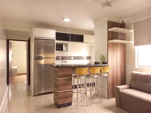 uma cozinha com um frigorífico de aço inoxidável e bancos de bar em Residencial Nicole em Florianópolis