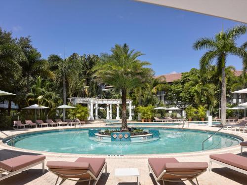 une grande piscine avec des chaises et des palmiers dans l'établissement The Cottages at PGA National Resort, à Palm Beach Gardens