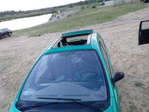a green car parked on the beach with its hood up at Wakacyjny domek - Łaś Ogrody in Rzewnie