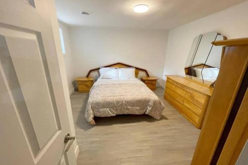 a bedroom with a bed and a wooden dresser at Stylish and luxurious apartment basement unit in Longueuil