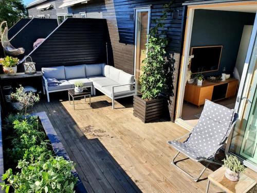 a patio with a couch and chairs and plants at Lys leilighet med fine uteplasser in Fredrikstad