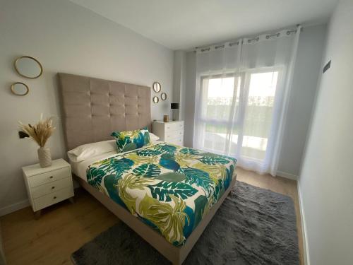 Un dormitorio con una cama grande y una ventana en Apartamentos modernos Residencial el Pinar, en Liencres