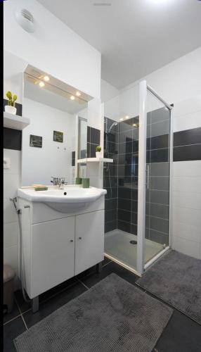 une salle de bain blanche avec une douche et un lavabo dans l'établissement Chez Pasqua ! Appartement spacieux avec terrasse 2 chambres 6 couchages en Rooftop, à LʼÎle-Rousse