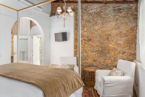 a bedroom with a bed and two white chairs at Le Rondini- Solo Adultos in Montrás