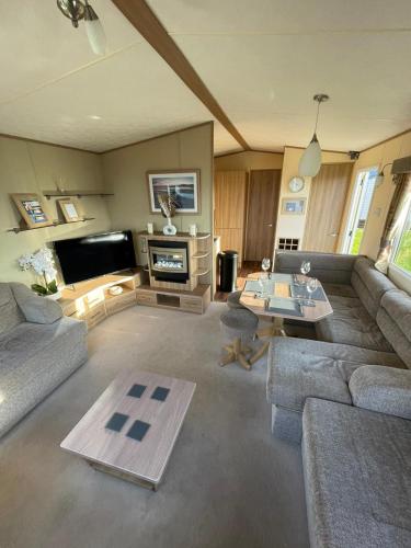 a living room with a couch and a table at Golden Palm Resort - Appleby - Coastal Caravan Breaks in Chapel Saint Leonards