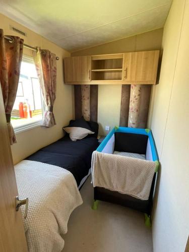 a small room with a bed and a small bed sidx sidx sidx sidx at Golden Palm Resort - Appleby - Coastal Caravan Breaks in Chapel Saint Leonards