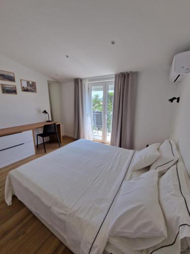 a large white bed in a bedroom with a window at Apartmani Maritimo in Seline