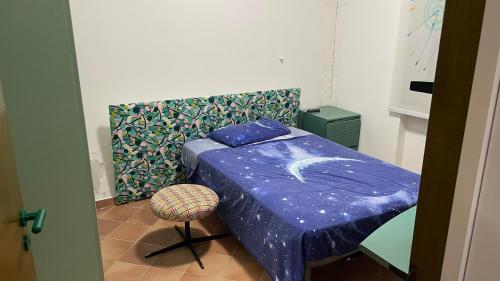 ein Schlafzimmer mit einem Bett mit einer blauen Bettdecke und einem Stuhl in der Unterkunft Villa Claudia Relais in Mirto