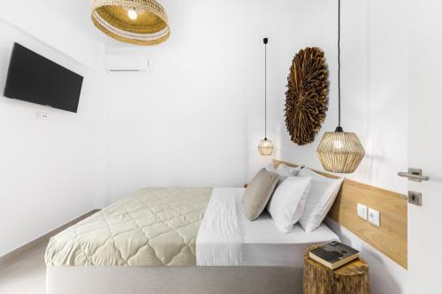 a white bedroom with a bed with a wooden headboard at Pel Mar in Pefkohori