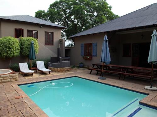 a swimming pool with two umbrellas and a house at East View Guesthouse in Pretoria