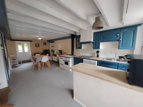 une grande cuisine avec des placards bleus et une salle à manger dans l'établissement Gîte du Connétable, à Couville