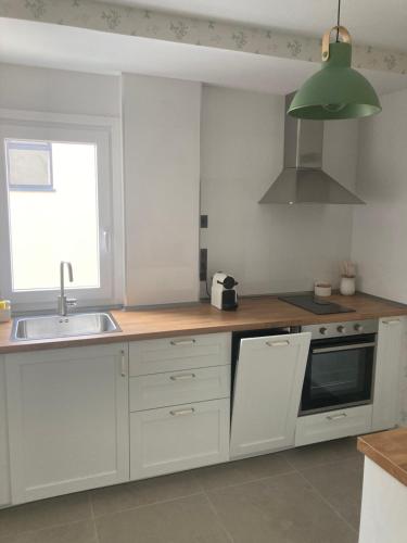 a kitchen with white cabinets and a sink and a window at Piso acogedor entre mar y montaña in Posada de Llanes