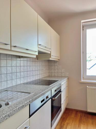 a kitchen with white cabinets and a window at Homely Stay Apartment 2 in Sankt Pölten