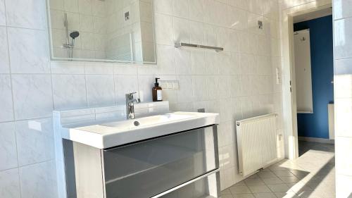 a white bathroom with a sink and a mirror at Homely Stay Apartment 2 in Sankt Pölten