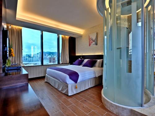 a bedroom with a large bed and a large window at The Bauhinia Hotel - Tsim Sha Tsui in Hong Kong