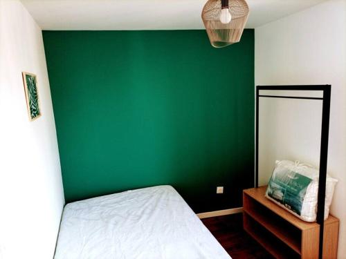 Un dormitorio con una pared verde y una cama en Maison de ville entière proche centre, en Amiens