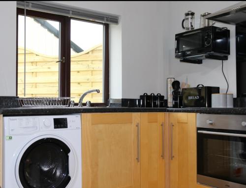 a kitchen with a washing machine and a window at The Snug At Kingfisher Cottage in Antrim