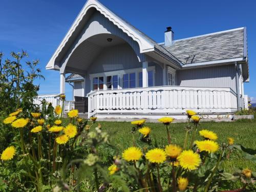 a house with a white fence and yellow flowers at BanPim Beachside Lofoten in Ramberg