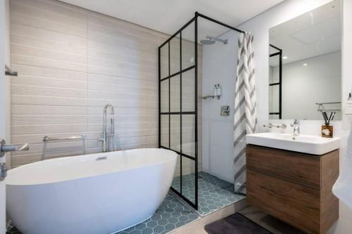 La salle de bains est pourvue d'une grande baignoire blanche et d'un lavabo. dans l'établissement Lux Oceans 2 Bedroom Apartment in Umhlanga, à Durban