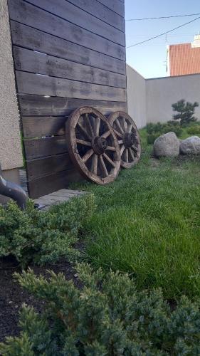 two old wooden wagon wheels sitting next to a building at the holiday house in Klaipėda