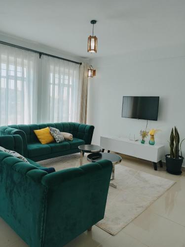 sala de estar con 2 sofás verdes y TV en Sky Nest Grey point 306, en Kericho