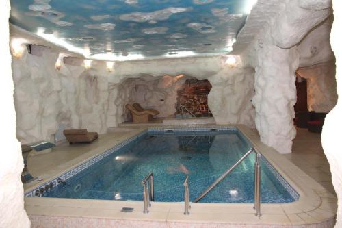 a large swimming pool in a room with a rock wall at Kleopatra VIP hotel in Kamianets-Podilskyi