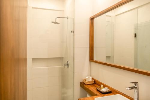 a bathroom with a shower and a sink and a mirror at Hotel Pelecanus Suites Holbox in Holbox Island