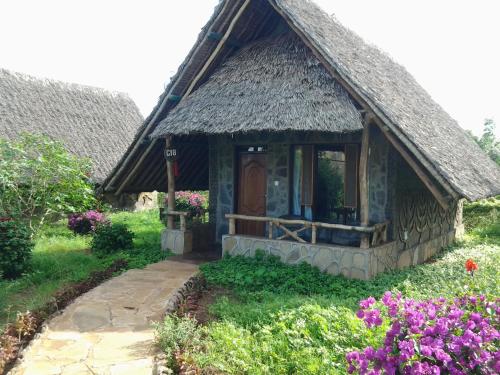 a small cottage with a thatched roof and a pathway at AA Lodge Amboseli in Amboseli