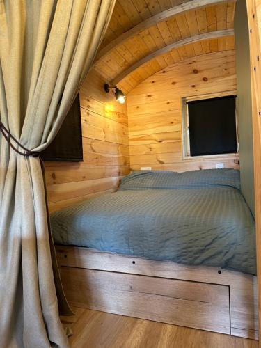 a bed in a log cabin with a window at La Roulotte de Loïs & Clara in Arc-en-Barrois