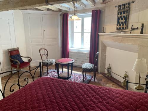 a bedroom with a bed and chairs and a fireplace at Le colombier in Le Coudray-Macouard