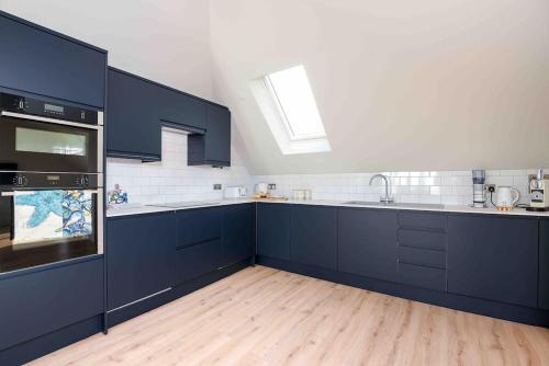 a large kitchen with blue cabinets and a skylight at Crow's Nest, Polperro in Polperro
